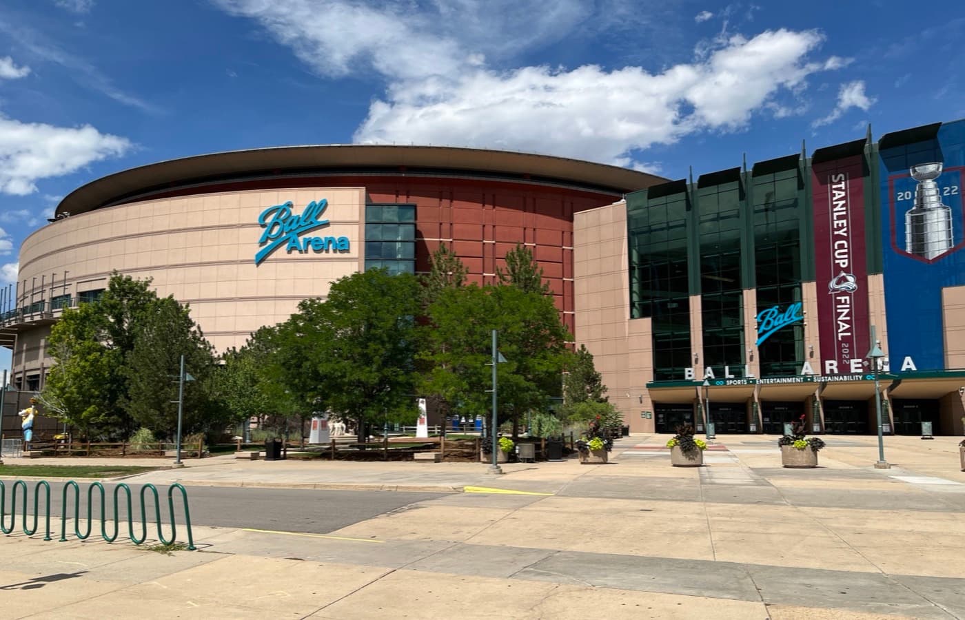 The rounded exterior of Ball Arena in Denver, with the Ball Arena sign on the tan and red facade and banners over the main entrance