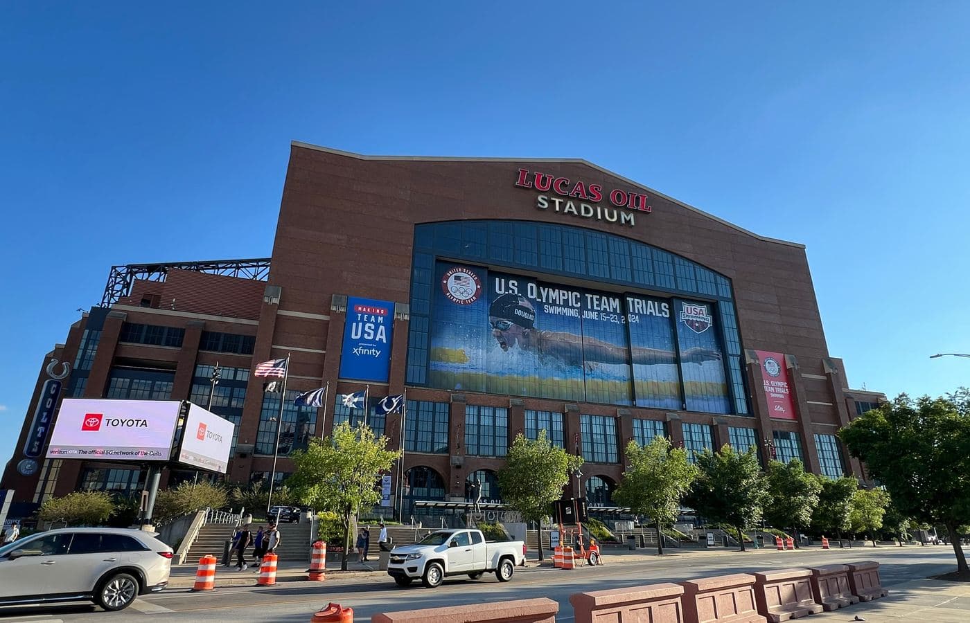 The brick north facade of Lucas Oil Stadium with its large glass window, seen from the street on a sunny day