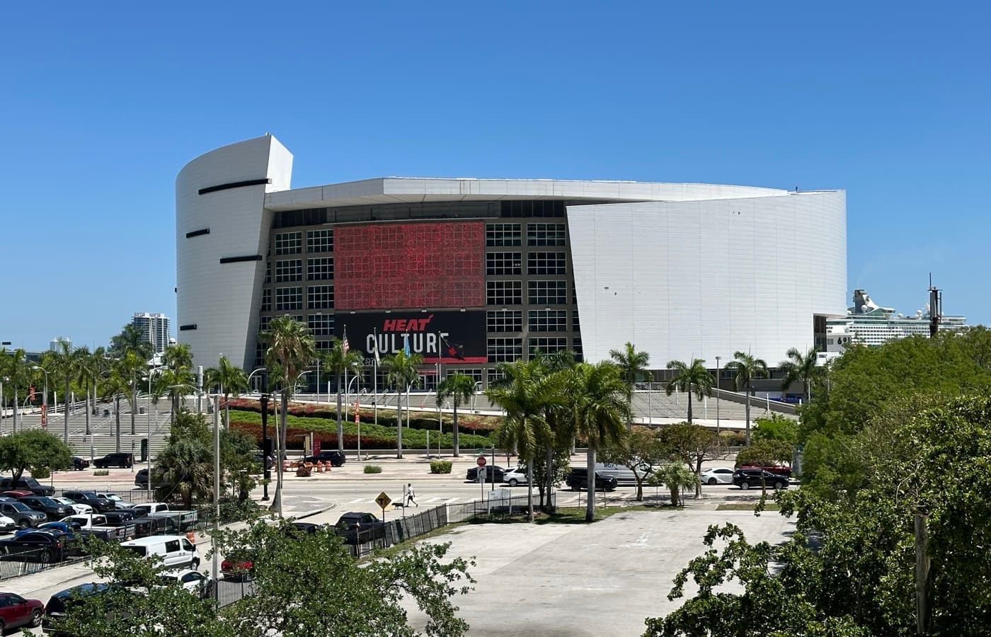 Kaseya Center’s white curved exterior on Biscayne Boulevard in downtown Miami, with palm trees and a HEAT Culture banner across the front glass