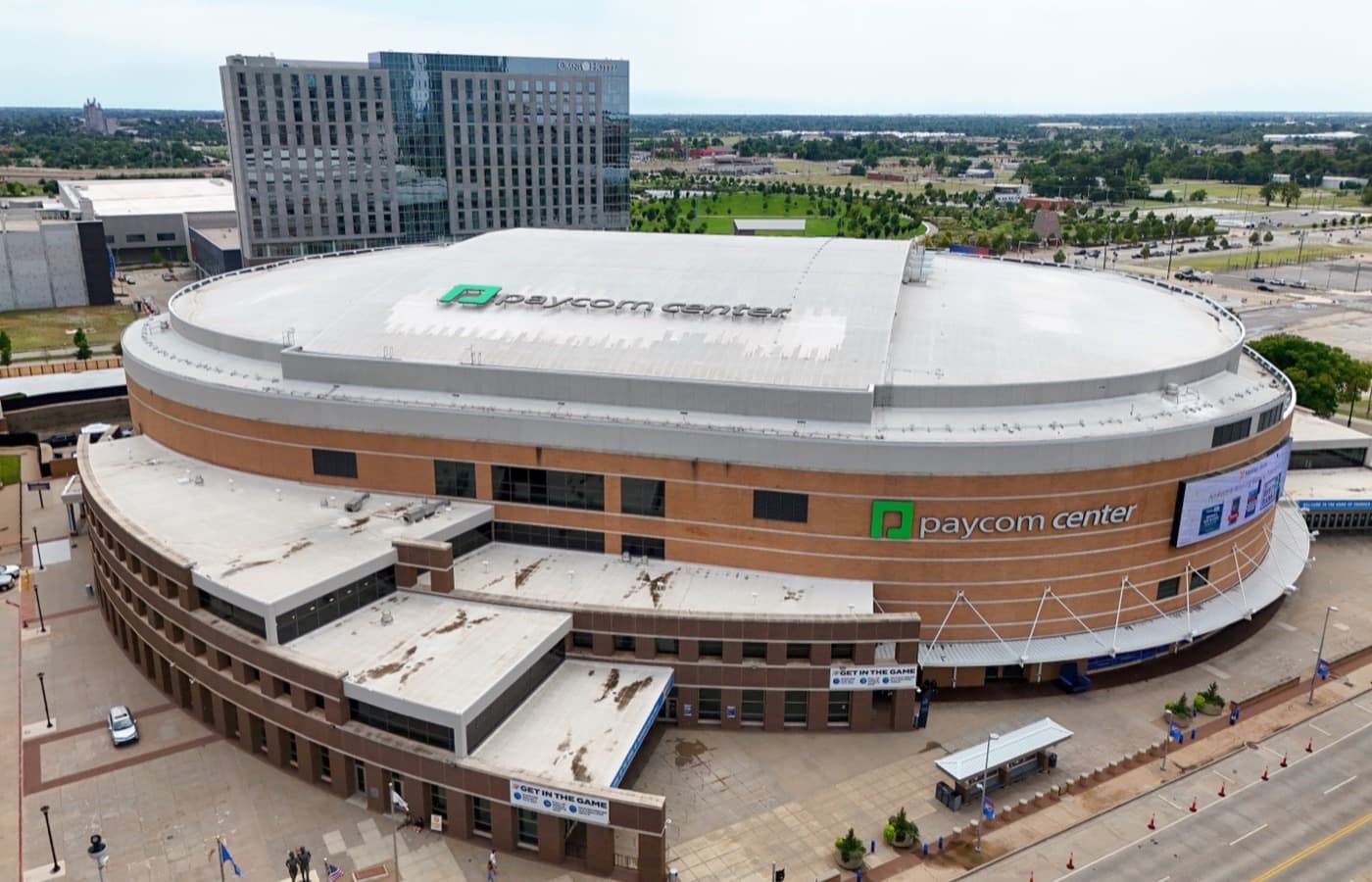 Aerial view of Paycom Center in downtown Oklahoma City, with the Omni hotel and Scissortail Park beyond it