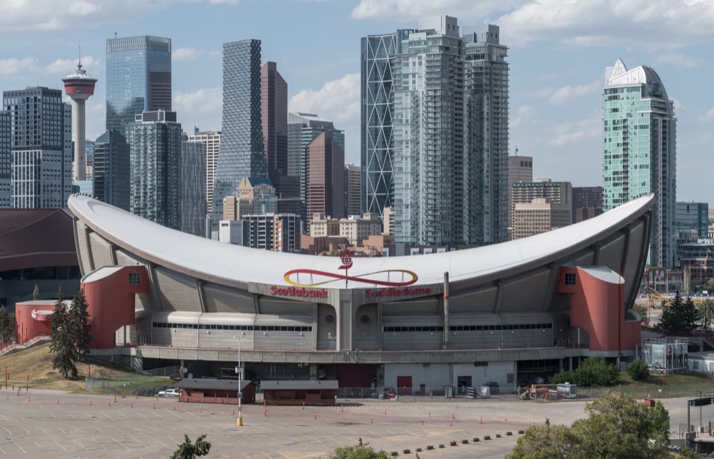 The Scotiabank Saddledome’s curved, saddle-shaped roof against the downtown Calgary skyline, including the Calgary Tower, on a clear day